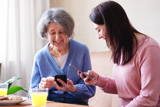A young woman helping her elderly relative with a mobile phone