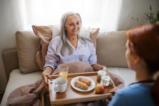 A live-in nurse bringing breakfast on a tray to a patient.