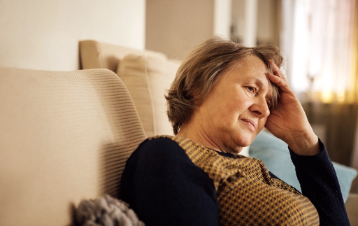 An elderly woman sat on her sofa looking tired