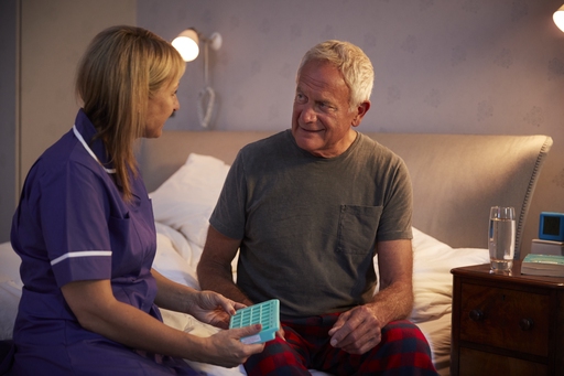 A carer supporting an older man to take medication
