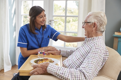 An elderly man being assisted in his own home by a carer