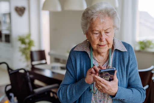 An elderly woman using a touch screen phone in her dining room