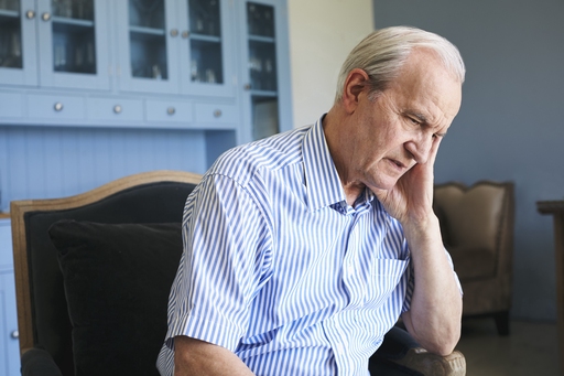 An older man looking tense and tired sat in an armchair