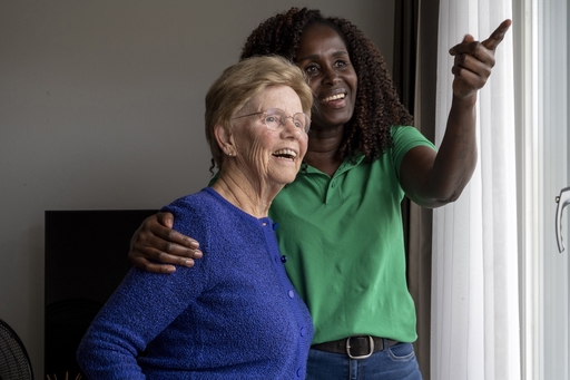 An elderly woman enjoying the view out of her window with a live-in carer.